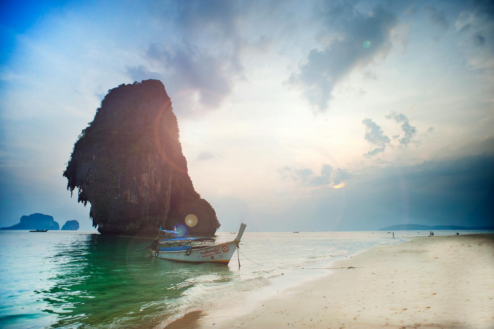 Bateau longtail au coucher du soleil face aux falaises d'Ao Nang, Krabi