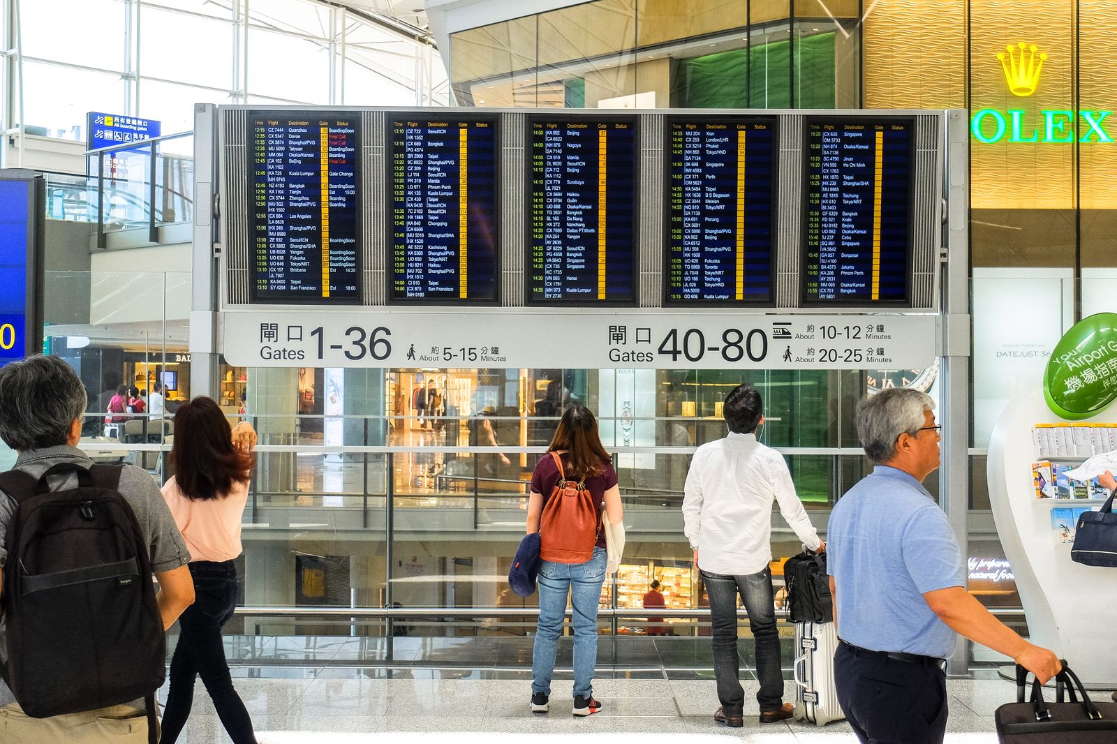 Voyageurs consultant les écrans d'affichage des départs dans un terminal d'aéroport