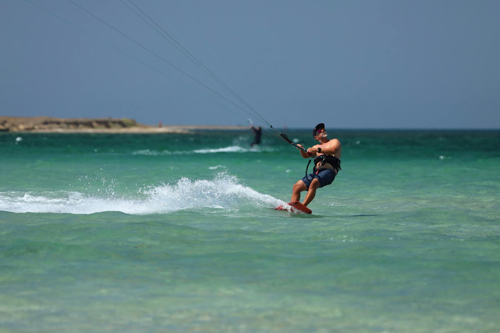 Kitesurfeur évoluant sur des eaux turquoise peu profondes sous un ciel dégagé