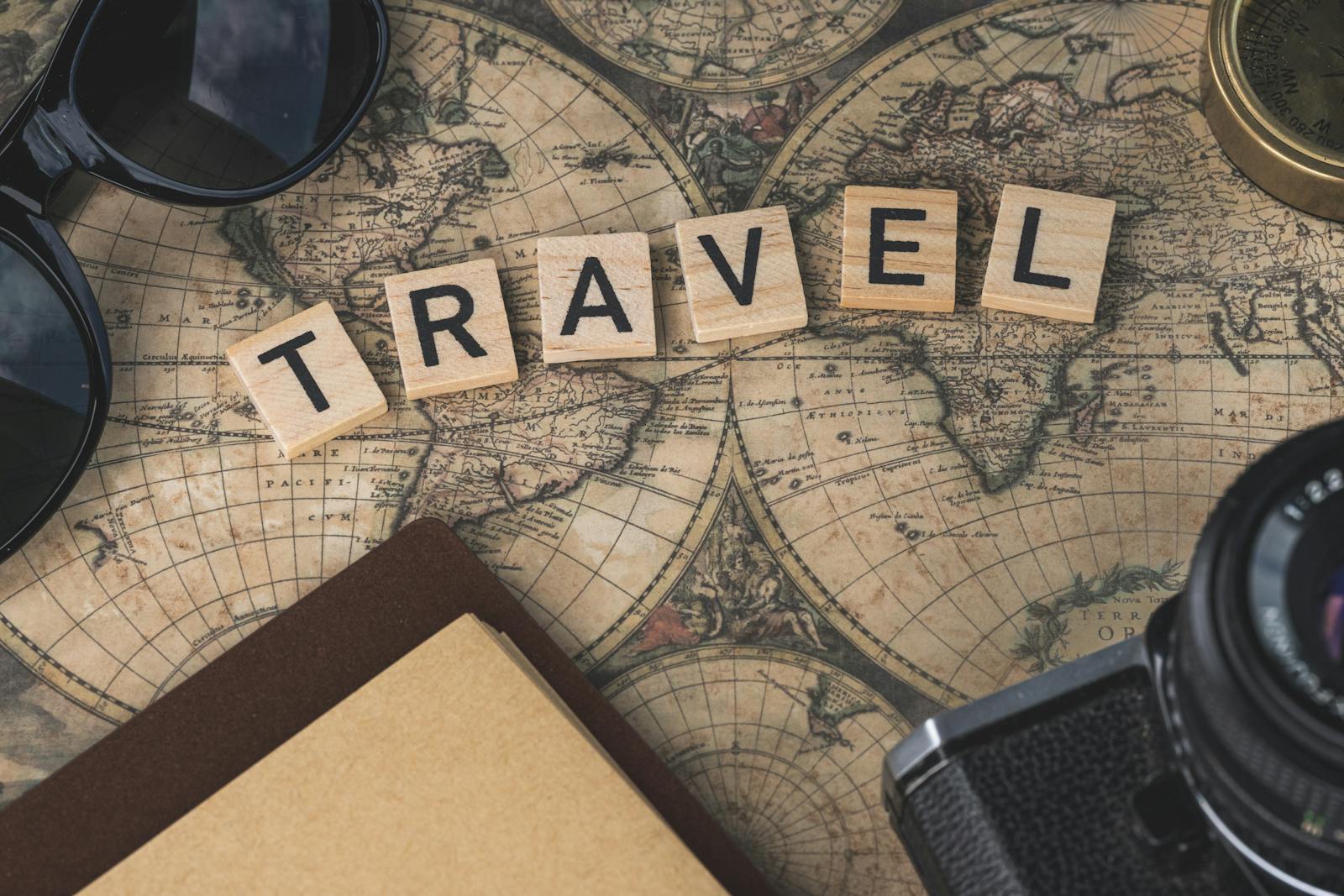 Lettres Scrabble formant le mot TRAVEL posées sur une carte du monde vintage