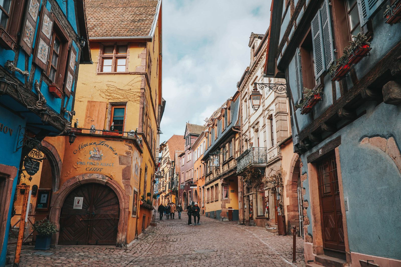 Ruelle pavée et maisons à colombages colorées d'un village de la route des vins d'Alsace