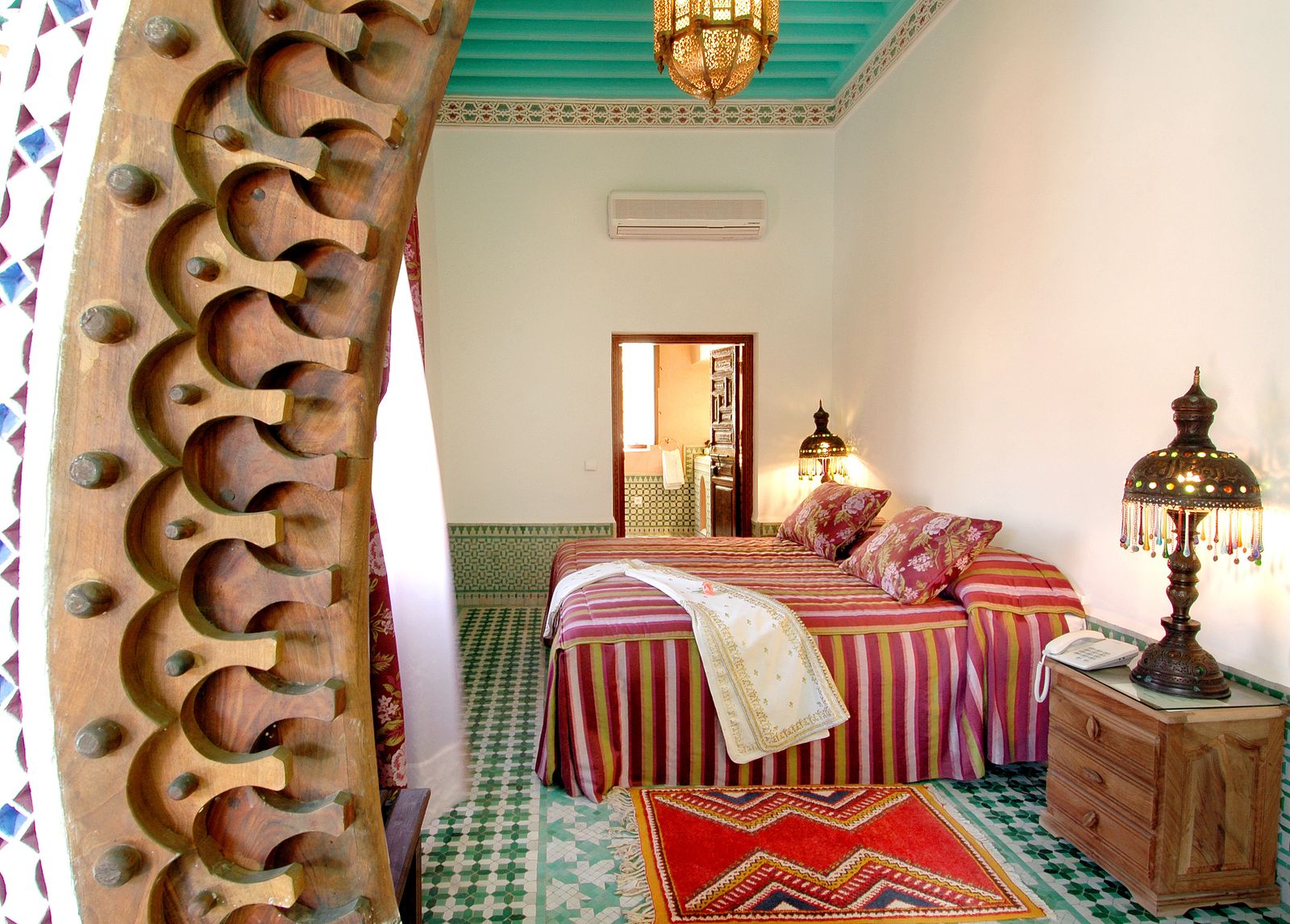 Chambre de riad marocain à Marrakech avec décoration traditionnelle et tissus colorés