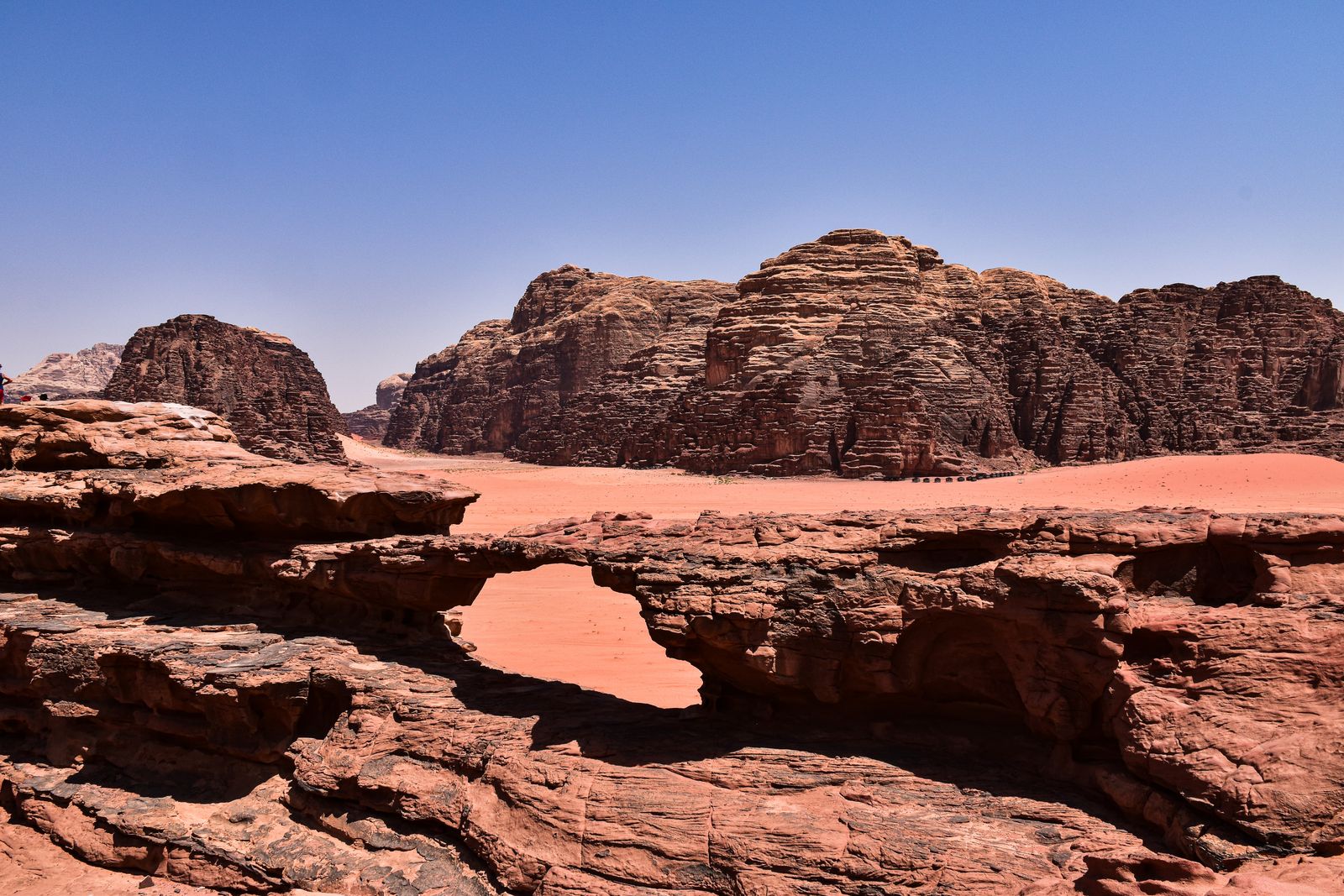 Formations de grès et dunes orangées du désert du Wadi Rum sous un ciel dégagé