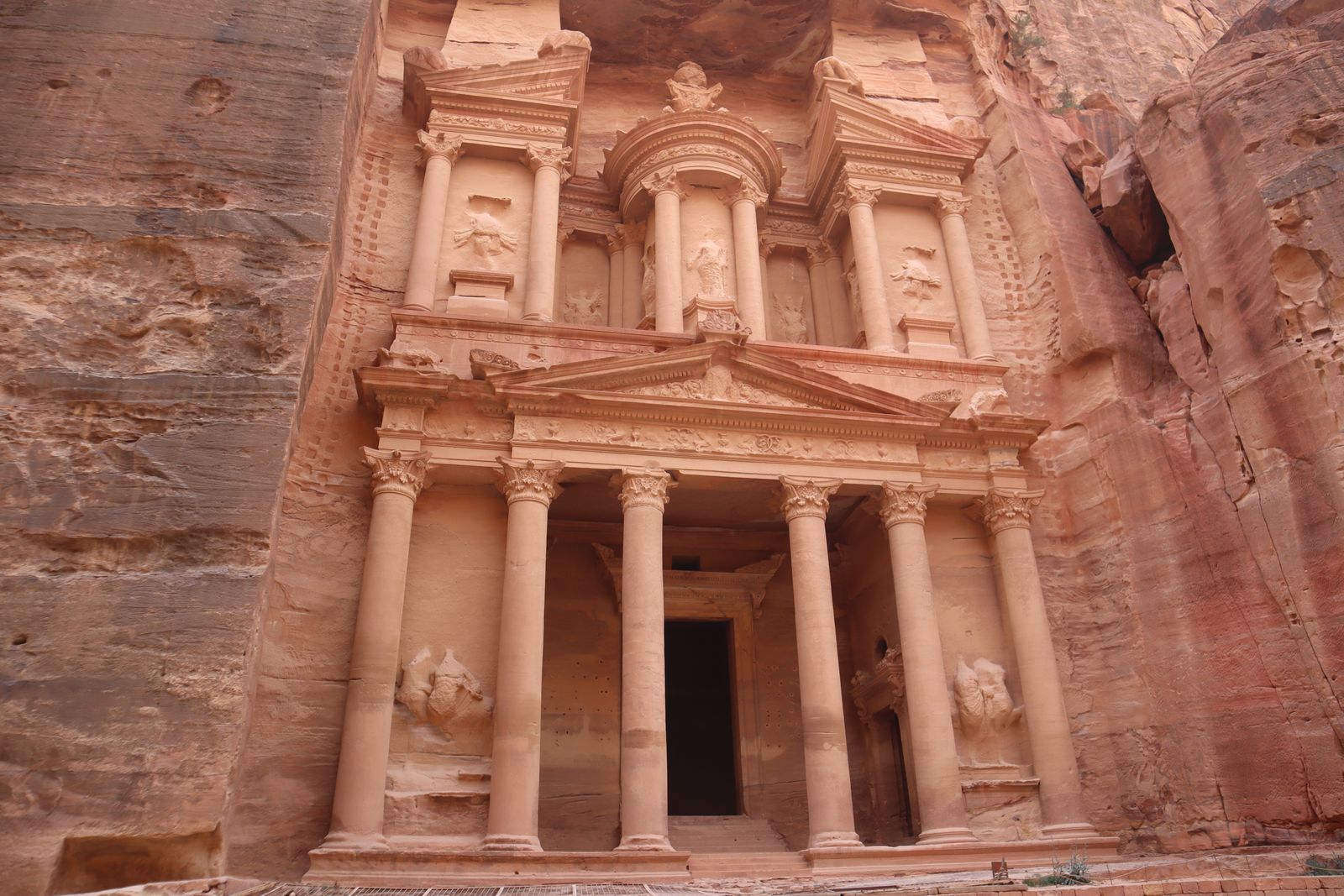 Façade du Trésor Al-Khazneh sculptée dans la roche rose de Pétra, vue depuis la sortie du Siq