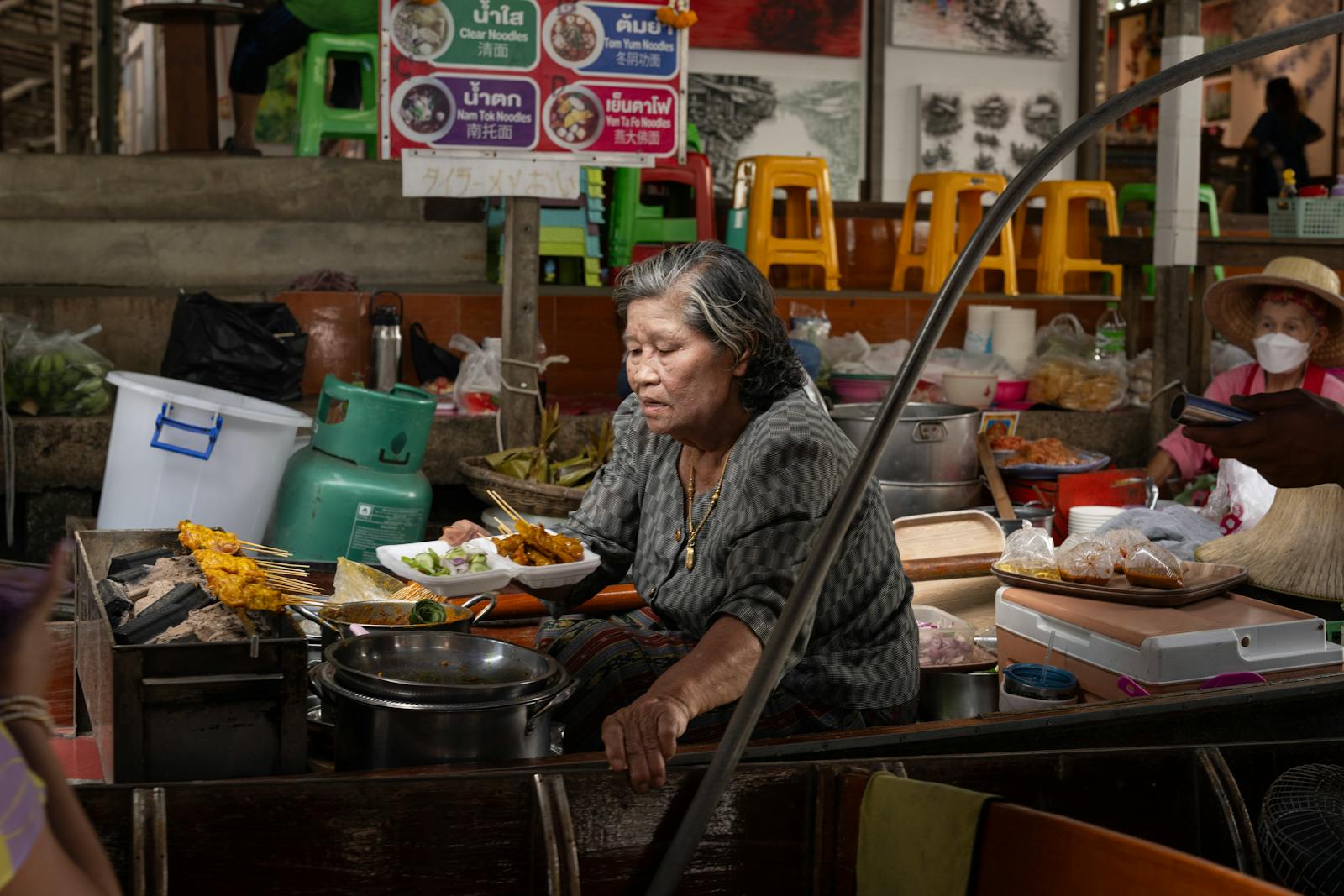 Cuisinière préparant des plats thaïs sur un marché de rue animé de Bangkok