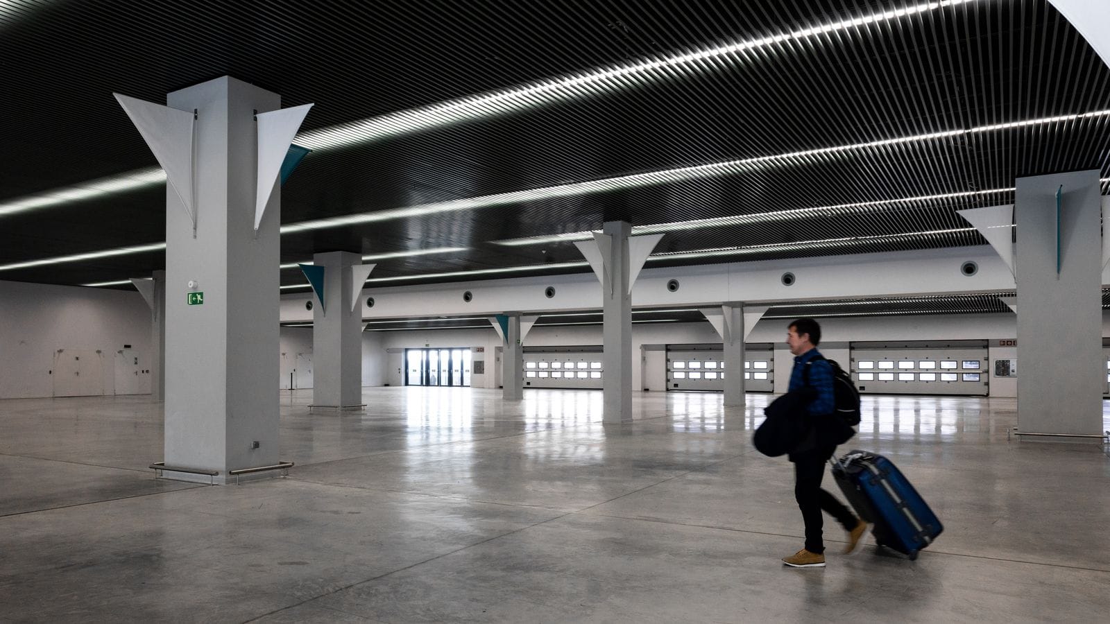 Voyageur avec ses bagages traversant un grand hall d'aéroport moderne