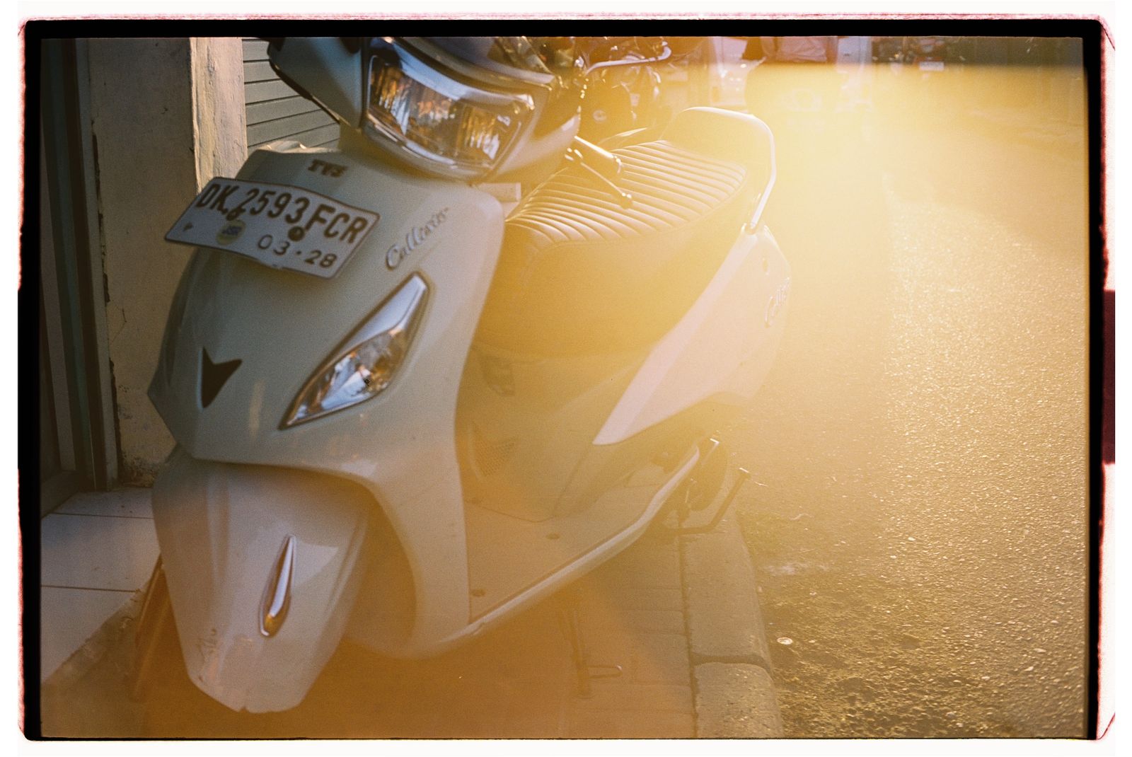 Scooter blanc stationné dans une rue ensoleillée de Bali