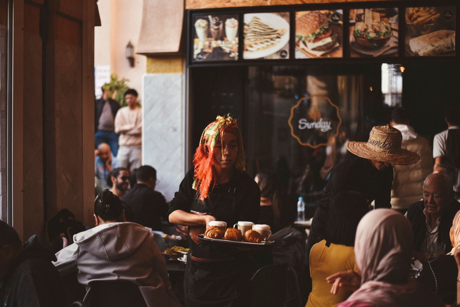 Café marocain animé avec serveuse, ambiance de terrasse traditionnelle