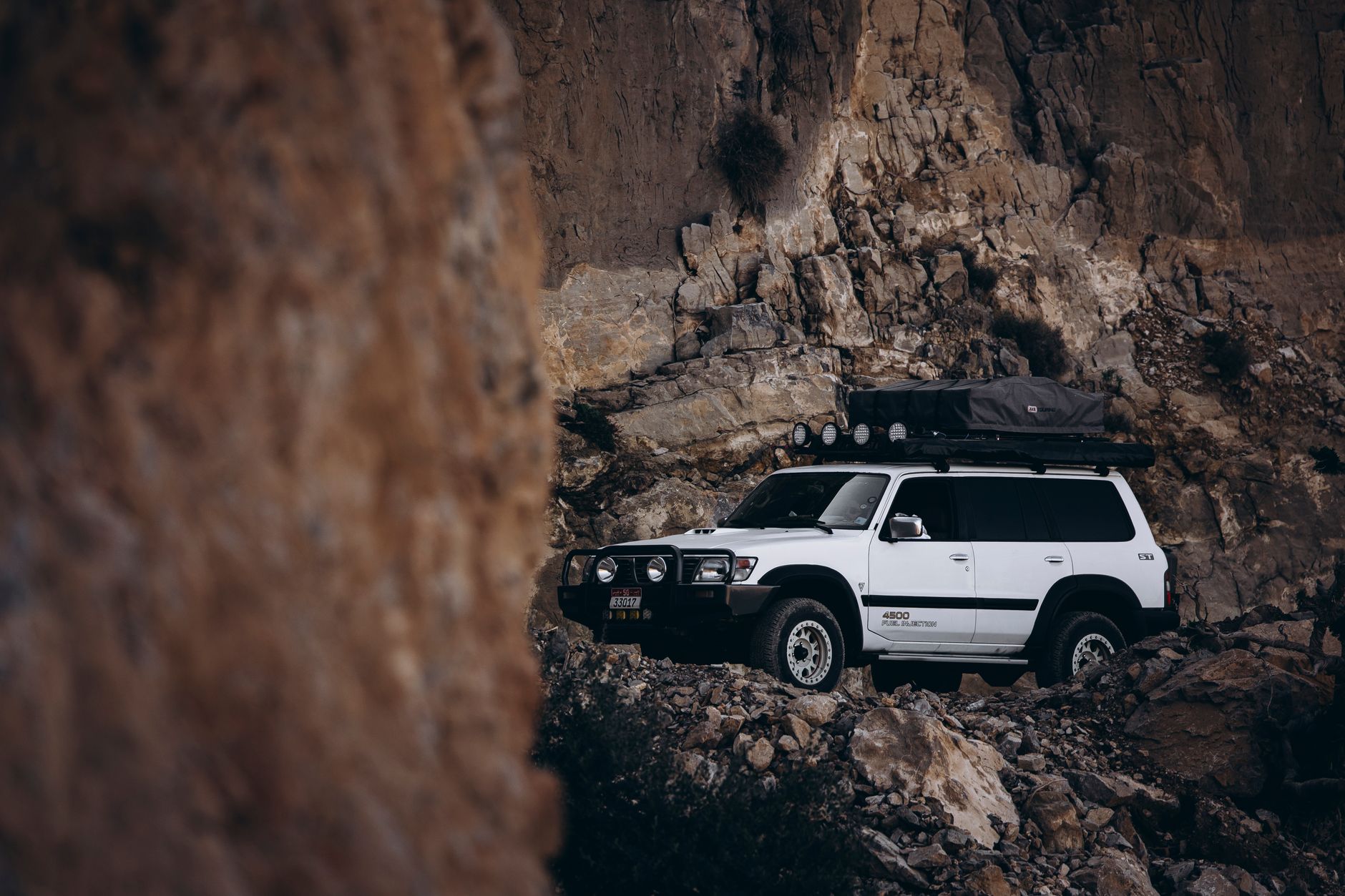 SUV franchissant un terrain rocheux dans un paysage aride d'Oman