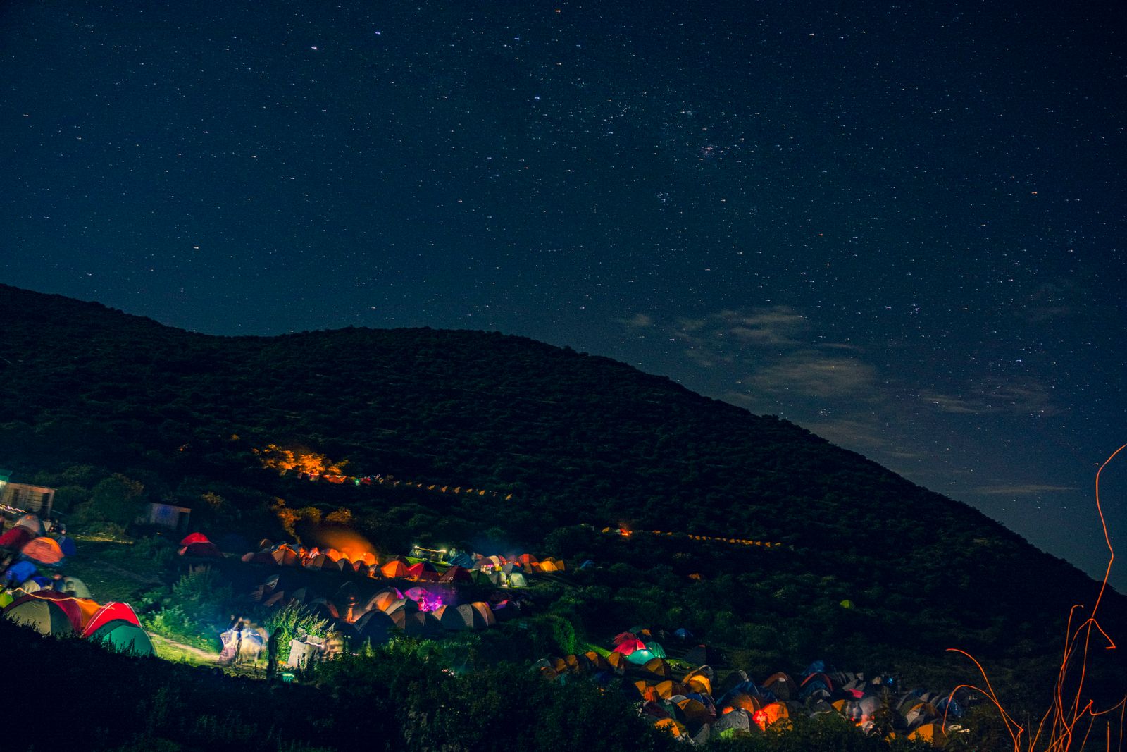 Tentes de campement éclairées sous un ciel étoilé dans le désert, Voie lactée visible