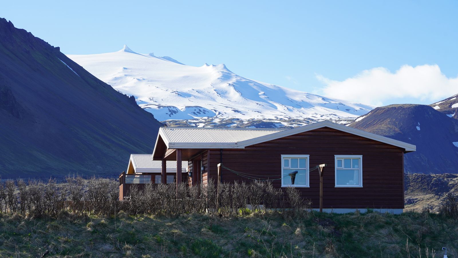 Cabane en bois isolée au pied des montagnes et glaciers islandais, typique des guesthouses rurales