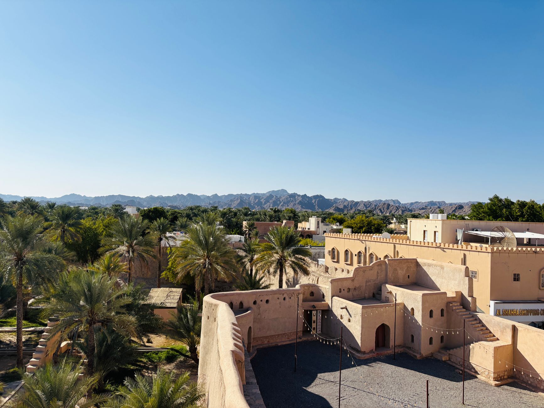 Fort de Nizwa et son oasis de palmiers devant les montagnes du Hajar, Oman