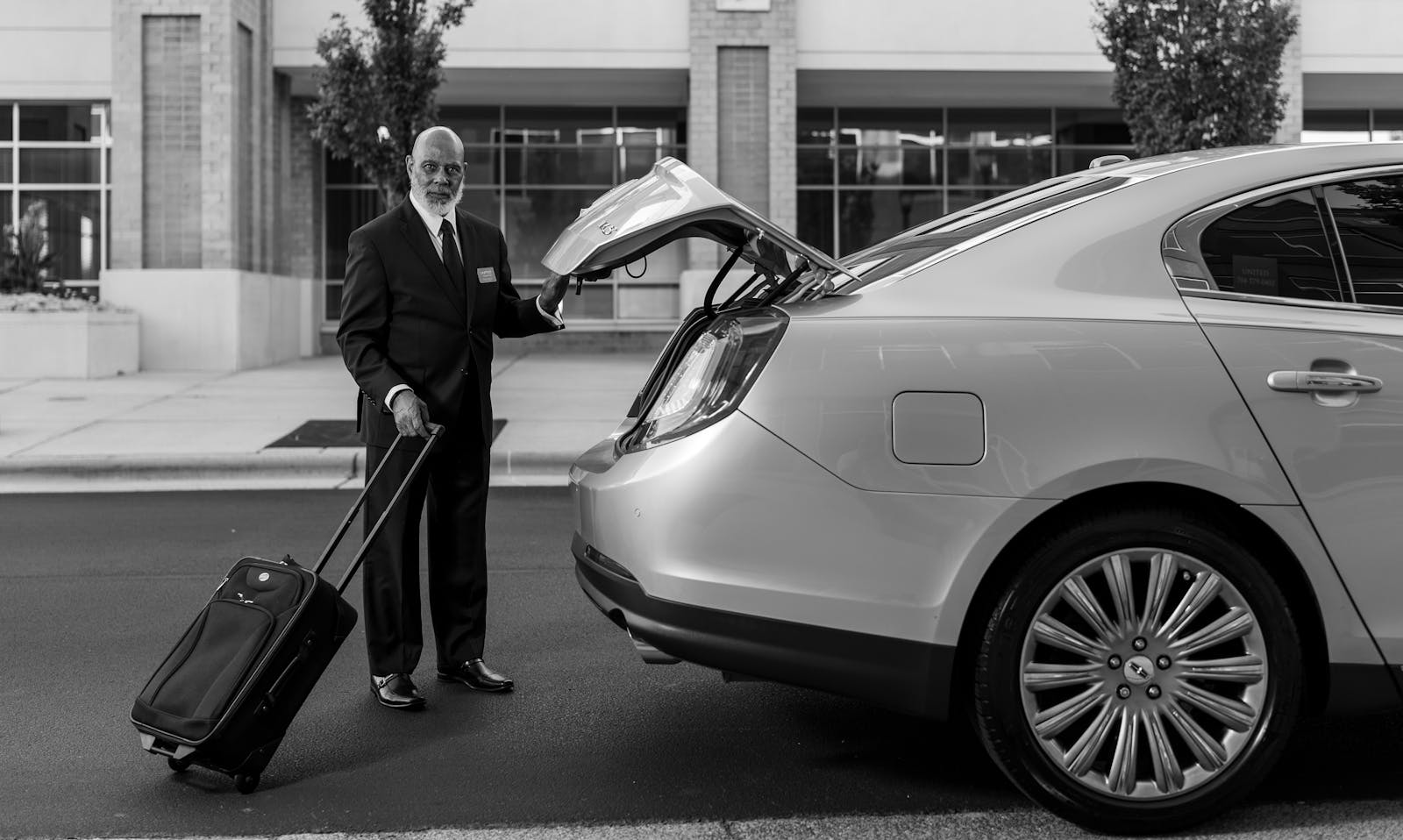 Chauffeur chargeant les bagages dans une voiture, transfert aéroport privé