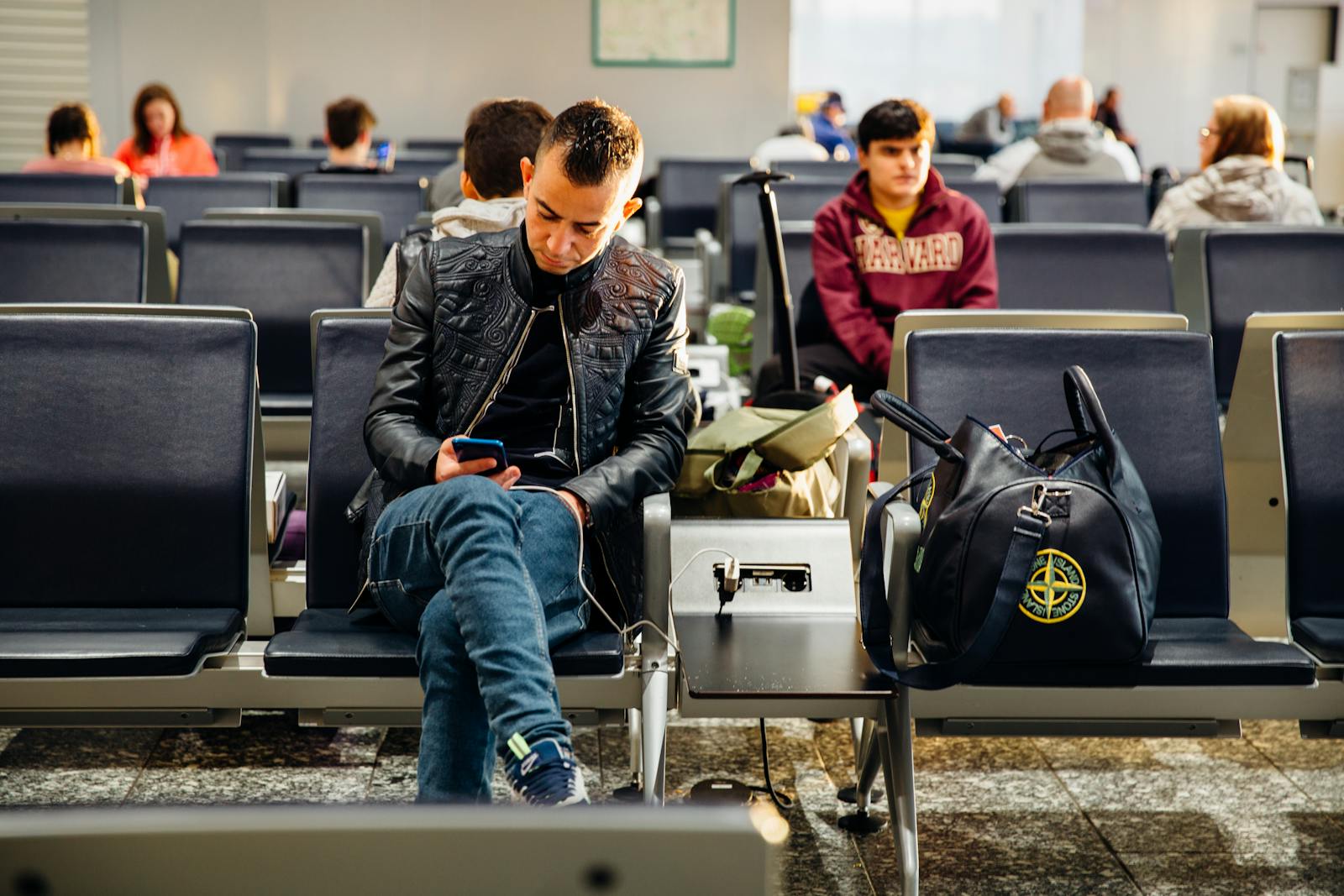 Voyageurs dans une salle d'embarquement d'aéroport, concentrés sur leur smartphone