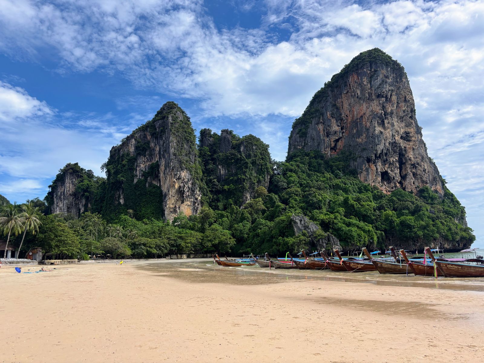 Bateaux longtail amarrés au pied des falaises calcaires de Railay Beach à Krabi