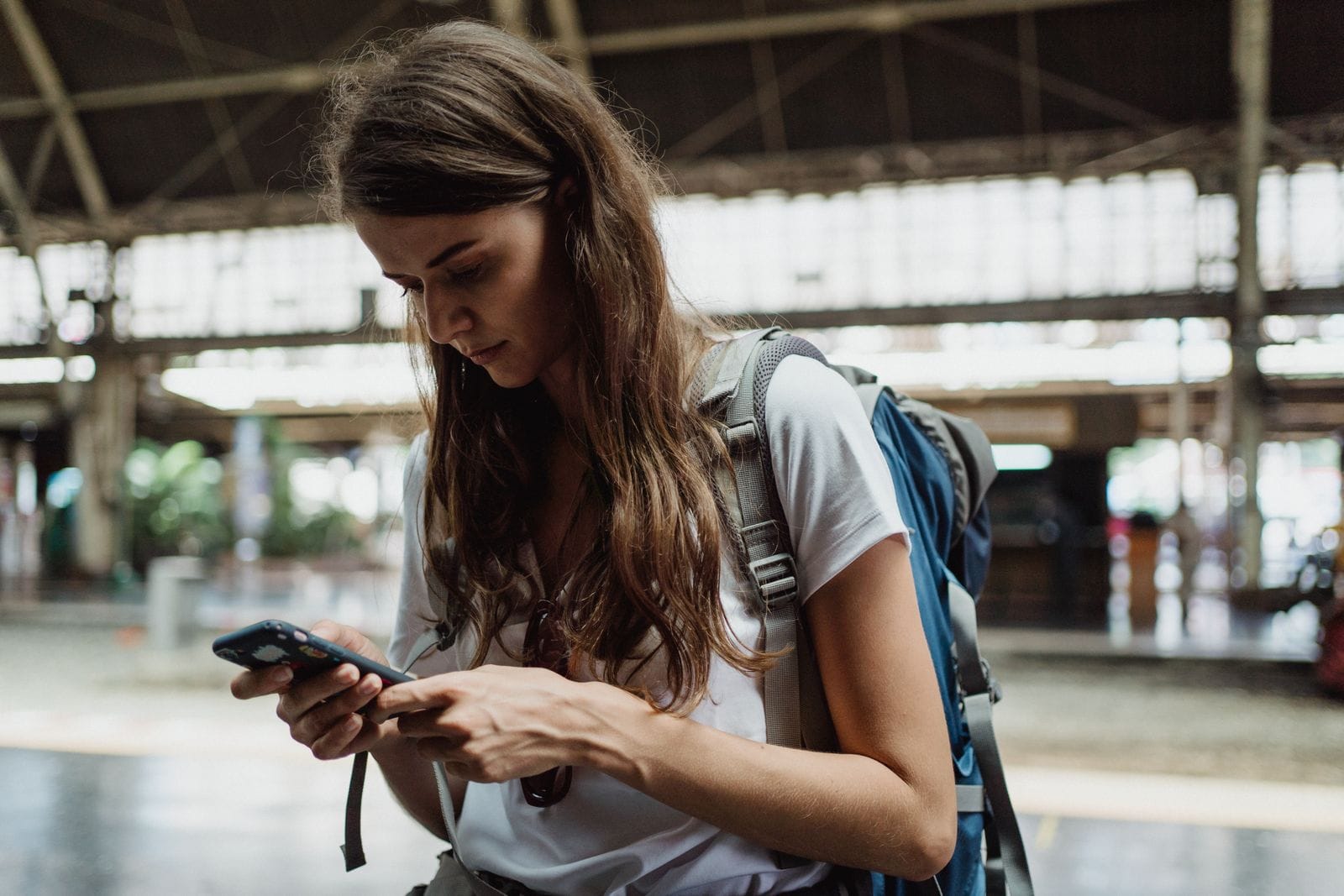 Voyageuse consultant son smartphone dans une gare, connectée pendant son trajet