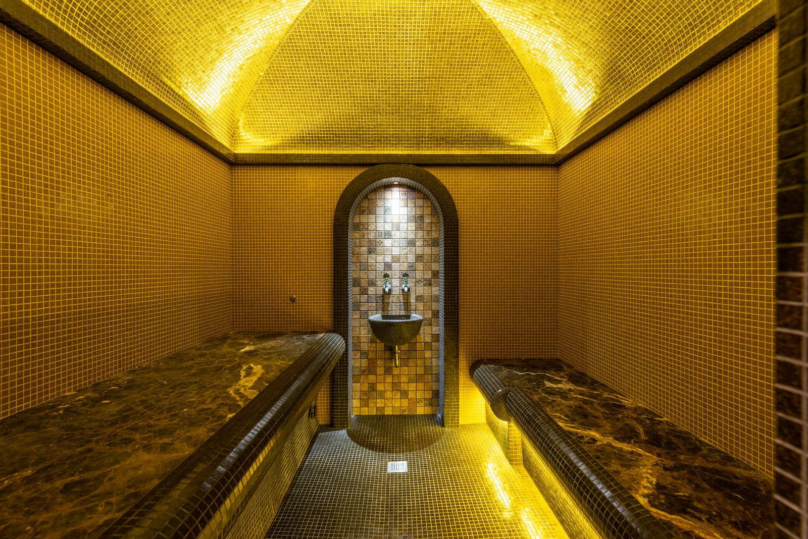 Intérieur en mosaïque d'un bain traditionnel avec éclairage chaleureux et banquettes de marbre