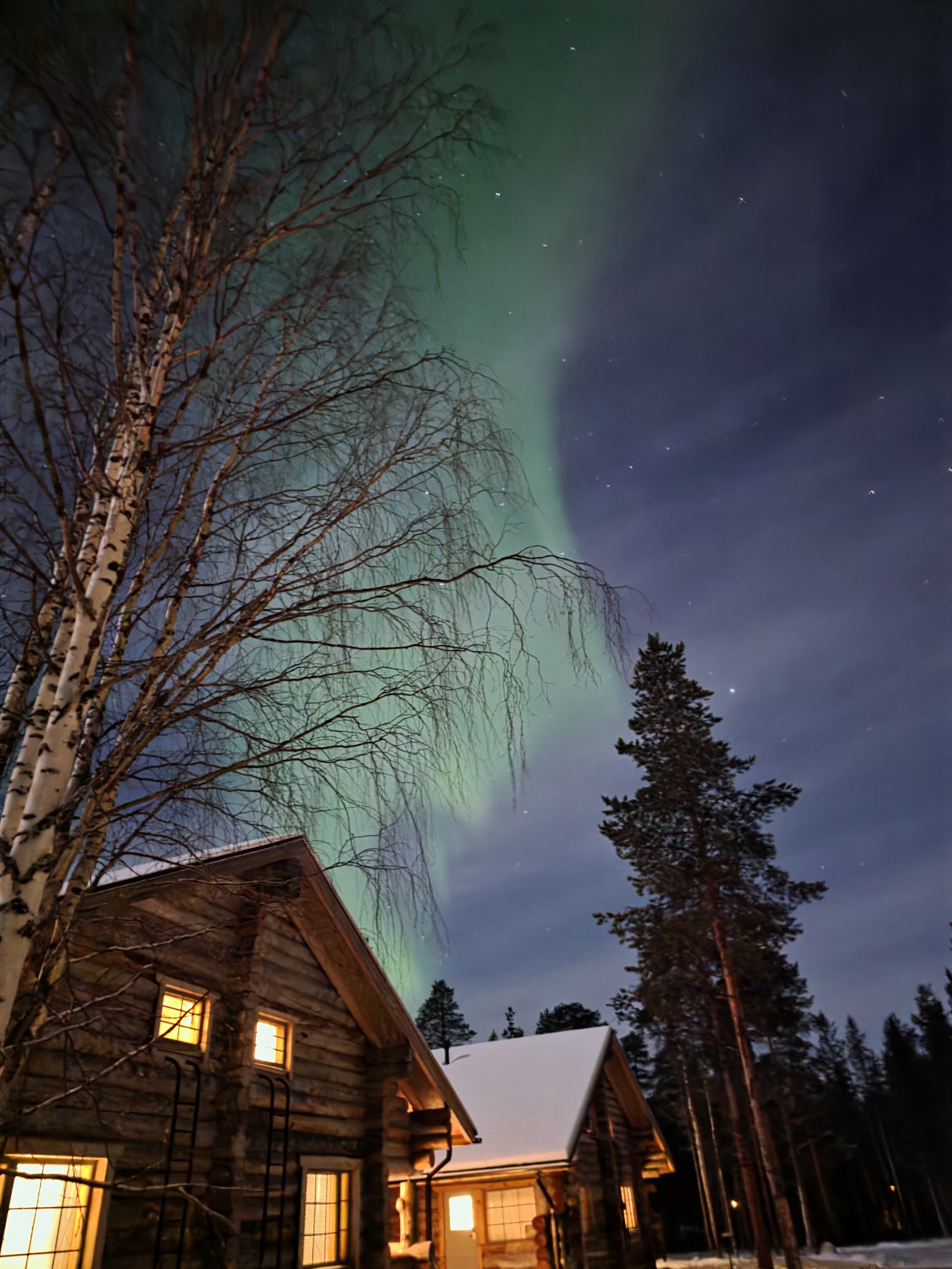 Cabines en bois avec aurores boréales au-dessus à Inari